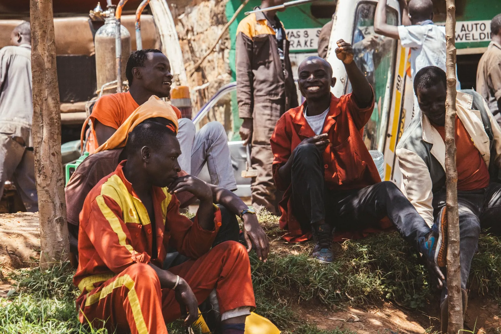 Mechanics in orange overalls sitting together outside a Nairobi garage